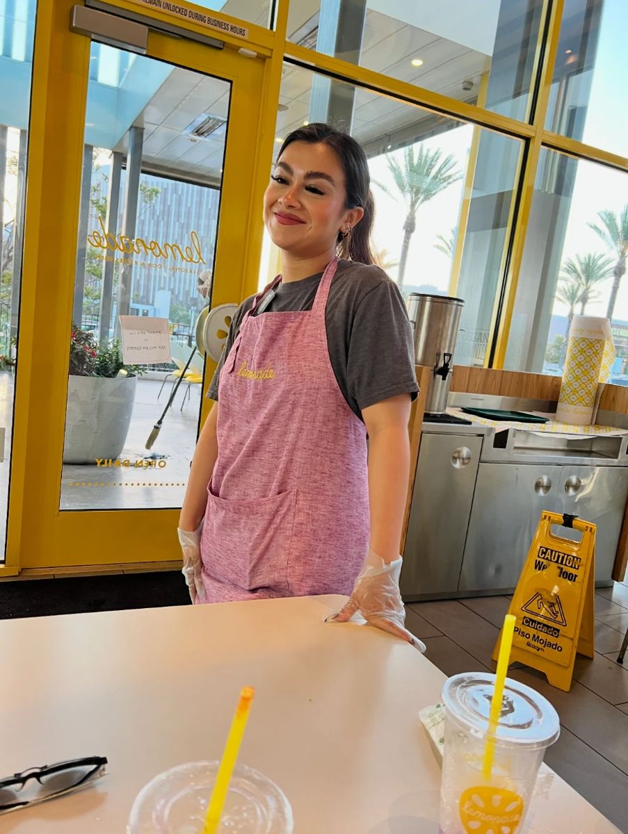 Gem smiling at work in a pink apron